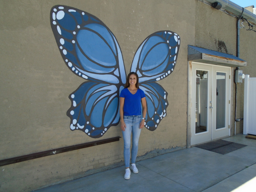Megan Mitchell in front of the butterfly that she painted on the north side of The Brewery. Photo by Lorraine Lieswald