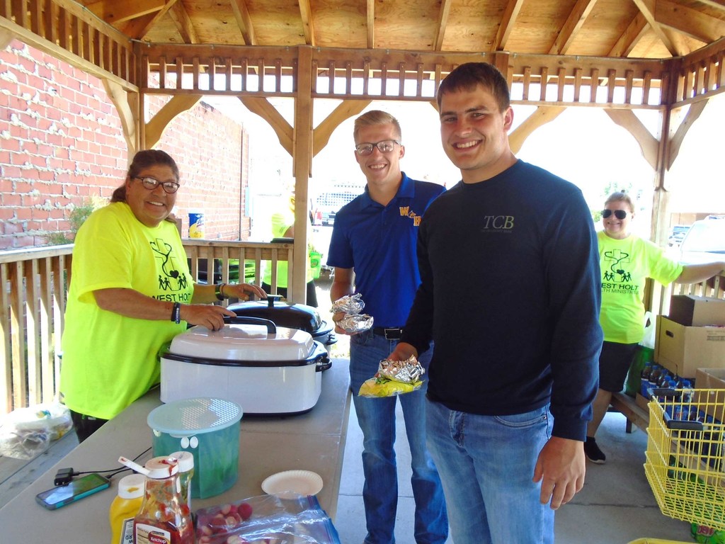 Linda Nekuda from the Atkinson -Stuart Food Pantry serves hamburgers to Bryce Kerkman and Tate Schmaderer after they made a donation to the Can Care-a-Van last Friday. Photo by Lorraine Lieswald