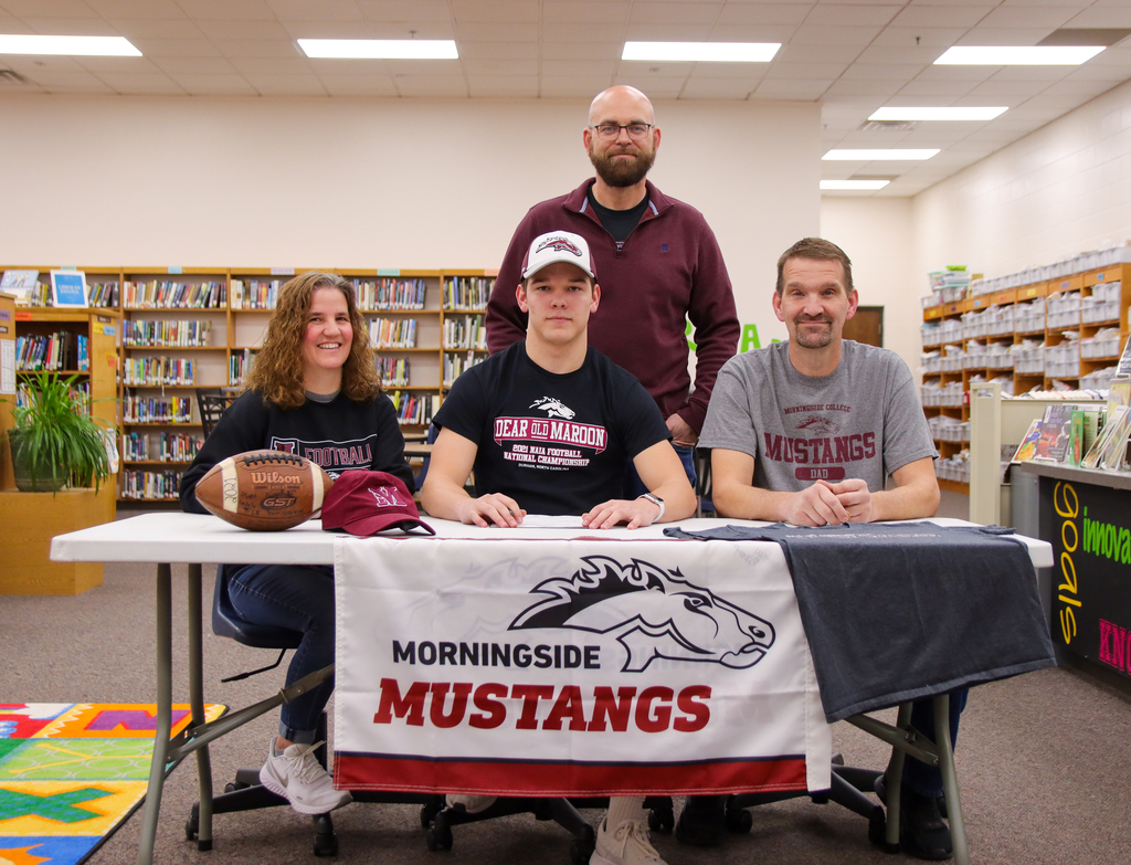 Logan Bokemper surrounded by his parents Carla and Russ and football coach Mike Hassler